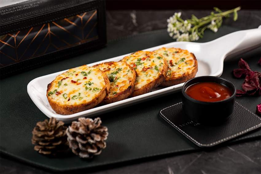 Cheese-stuffed garlic bread, golden on top, with a dip on the side.