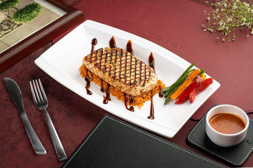 A savoury waffle finished with a drizzle and a scatter of vegetables.
