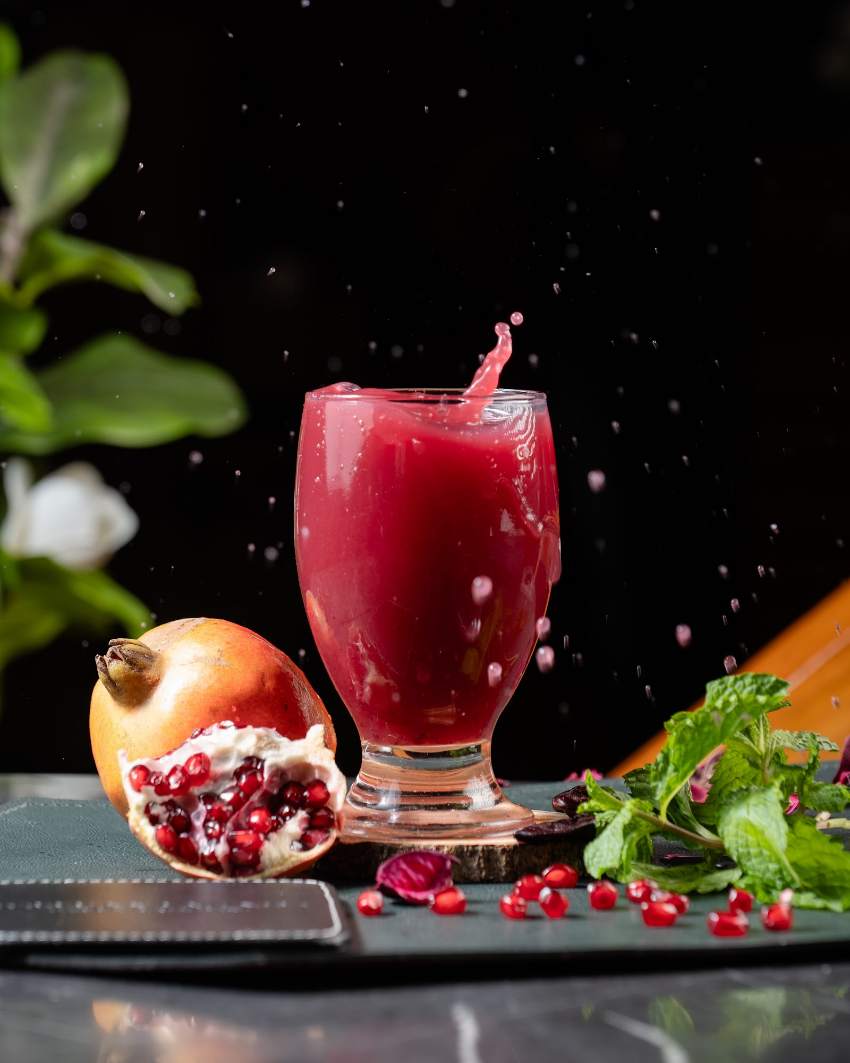 A pomegranate cooler caught mid-pour, fresh fruit alongside.